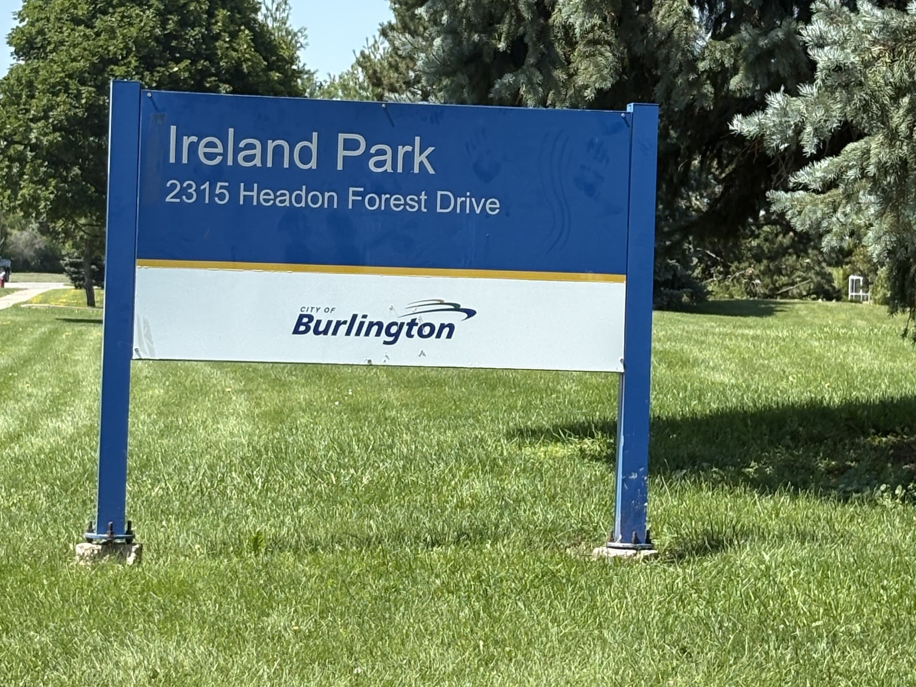 City of Burlington park sign reading Ireland Park, 2315 Headon Forest Drive, on a sunny lawn in Headon Forest.