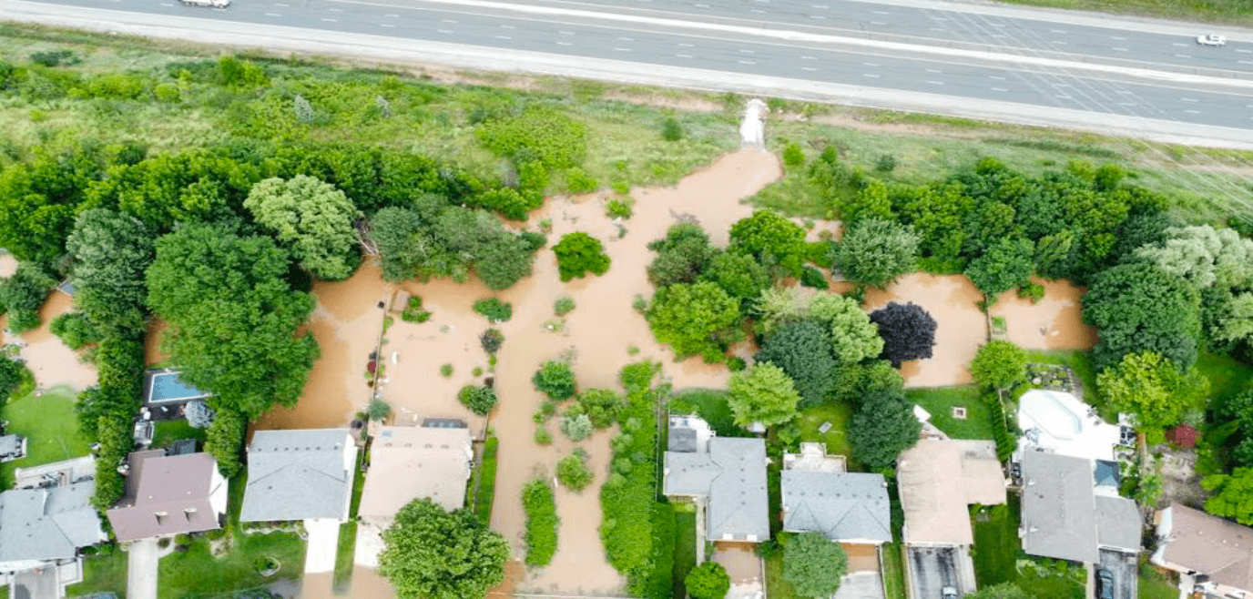 Aerial view of muddy floodwater covering backyards and green space between Highway 407 and Millcroft homes during the July 2024 storm.